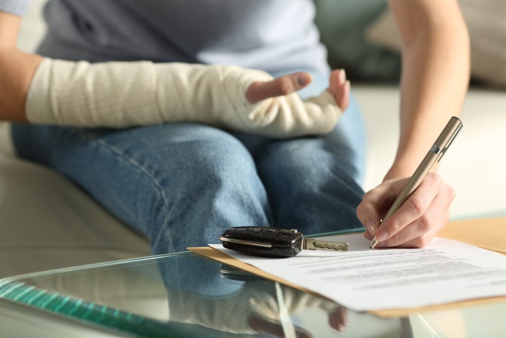 Close up of a lady hands with broken arm signing insurance document after car accident .